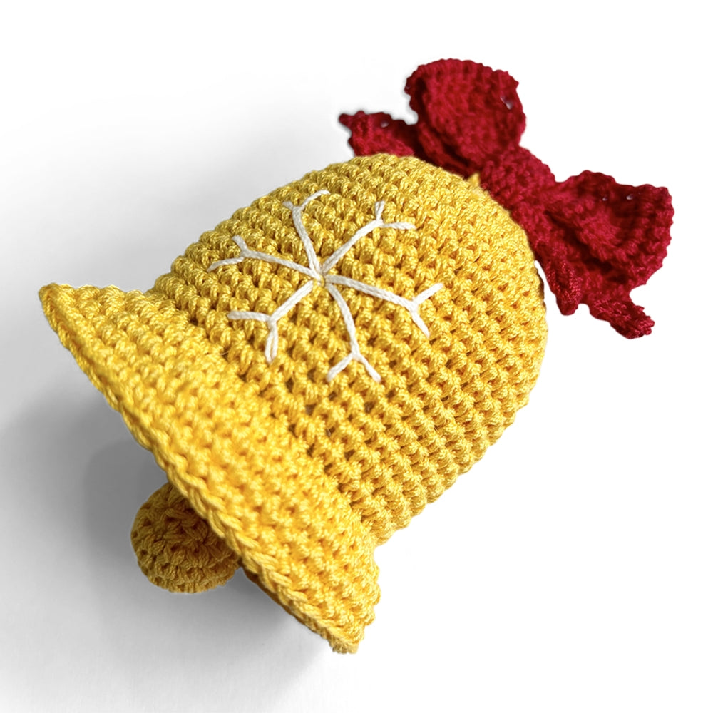 Crocheted dog toy bell with yellow crochet texture, red bow, and white snowflake motif