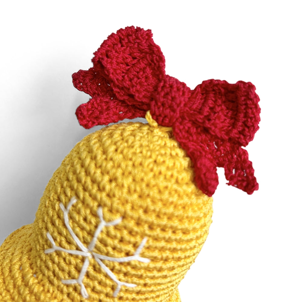 Crocheted dog toy bell with yellow body, red bow, and white snowflake stitching