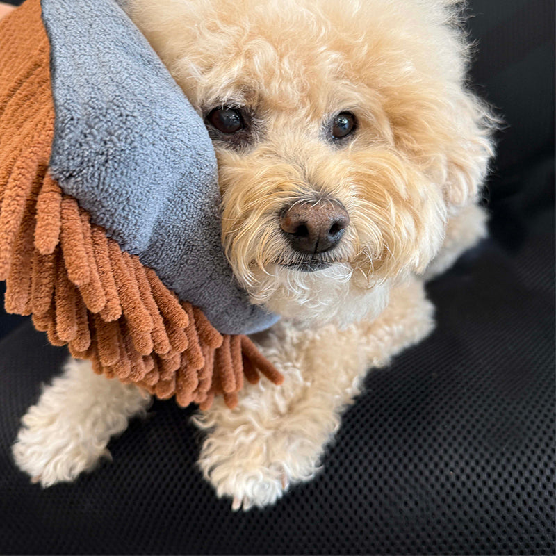 Dog lying with brown grooming mitt over the muzzle, featuring gray fabric backing