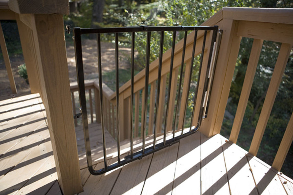 Black aluminum safety gate installed on wooden deck railing with vertical bars