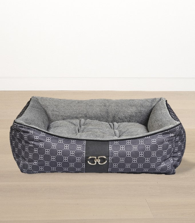 Scoop dog bed with gray cushion and dark patterned cover on a light wood floor