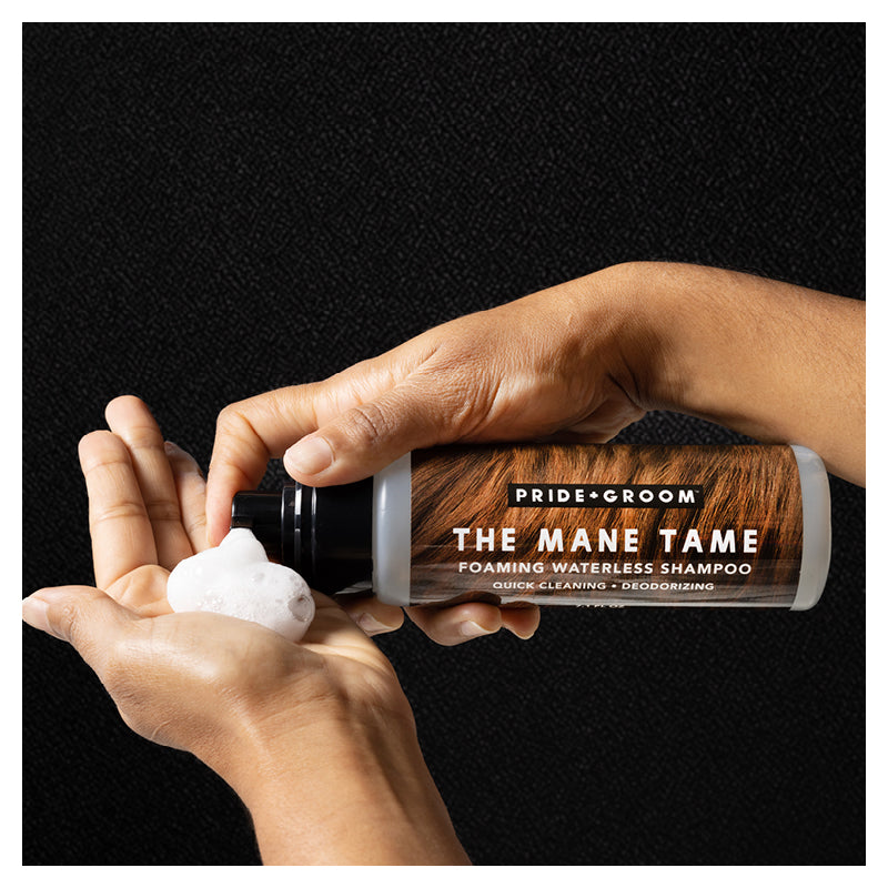 Hands dispensing foam from THE MANE TAME Pride+Groom waterless shampoo bottle