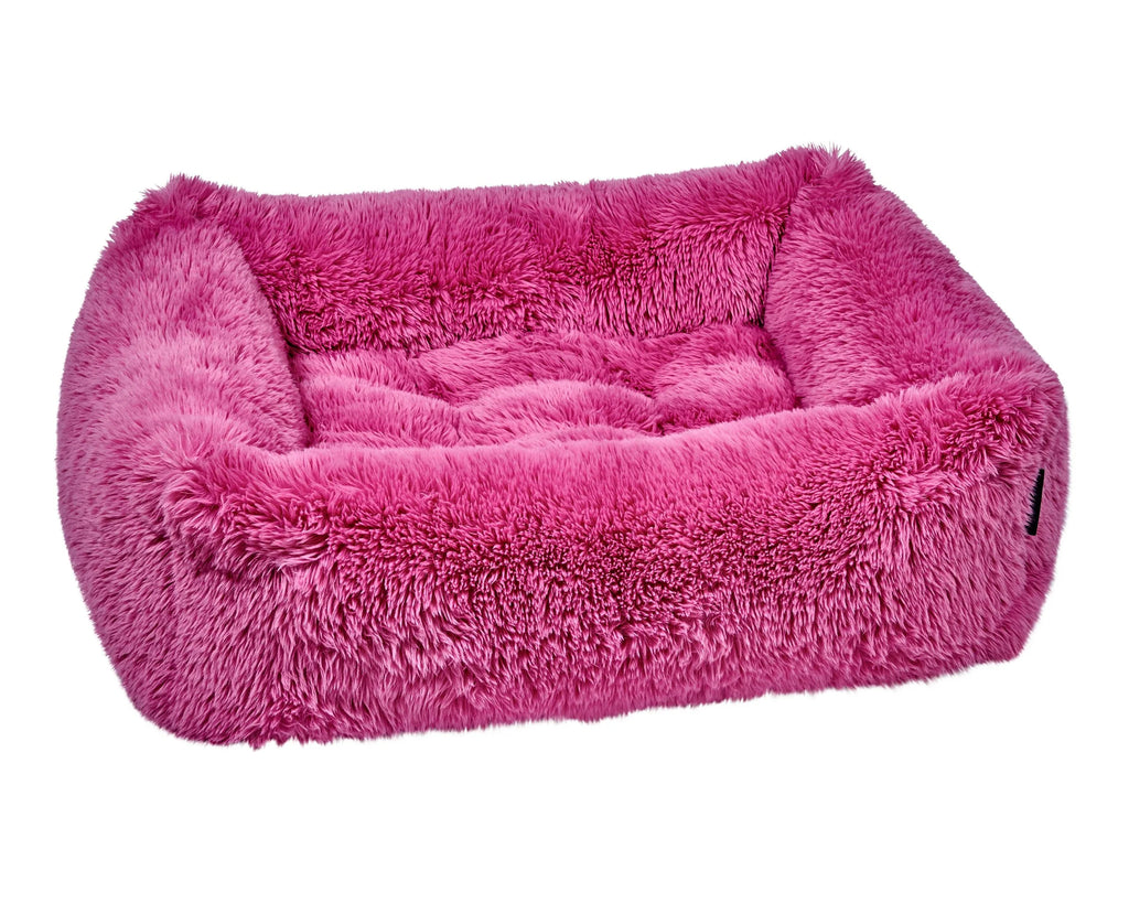 Pink plush dog bed with padded bolster sides and cushioned interior, rectangular shape