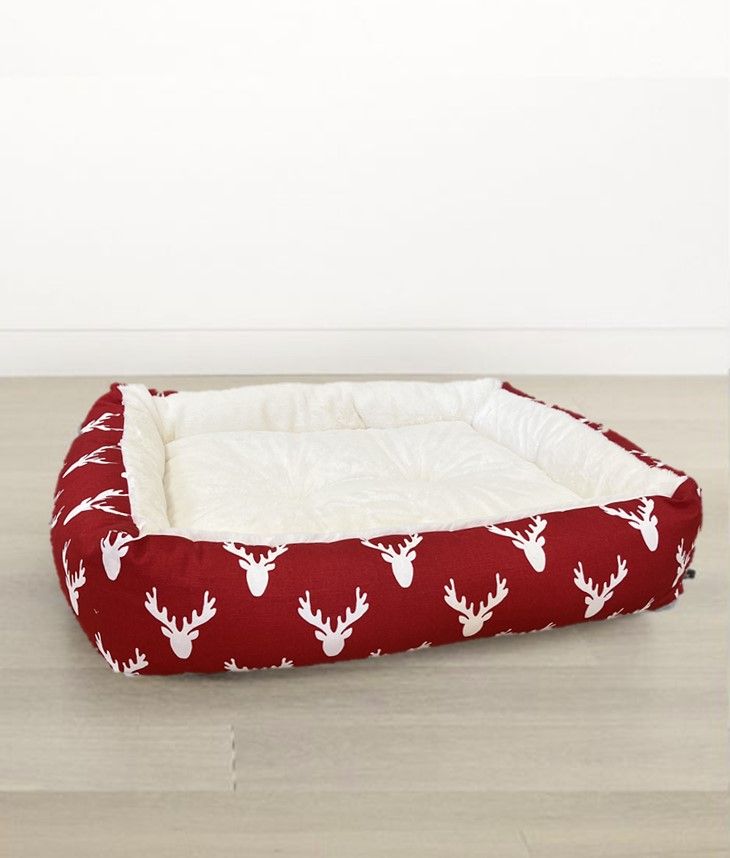 Red antler-print dog lounger bed with white padded cushion and rolled edges