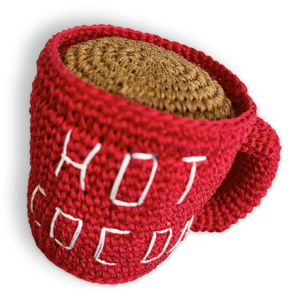 Red crochet mug dog toy with beige top filling and white stitched cocoa pattern