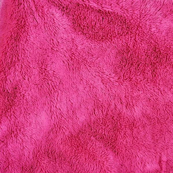 Close-up of bright pink faux fur dog blanket pile texture