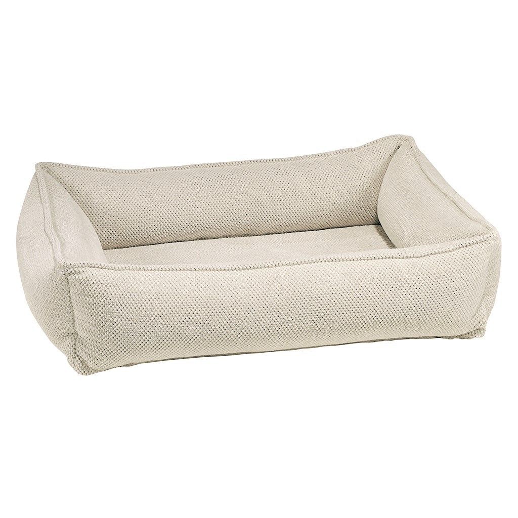 Light beige woven dog bed with rounded bolster sides and cushioned front