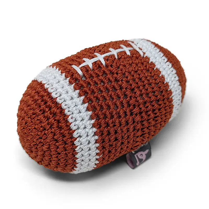 Crocheted football-shaped dog toy in dark brown with white stripes and textured stitches