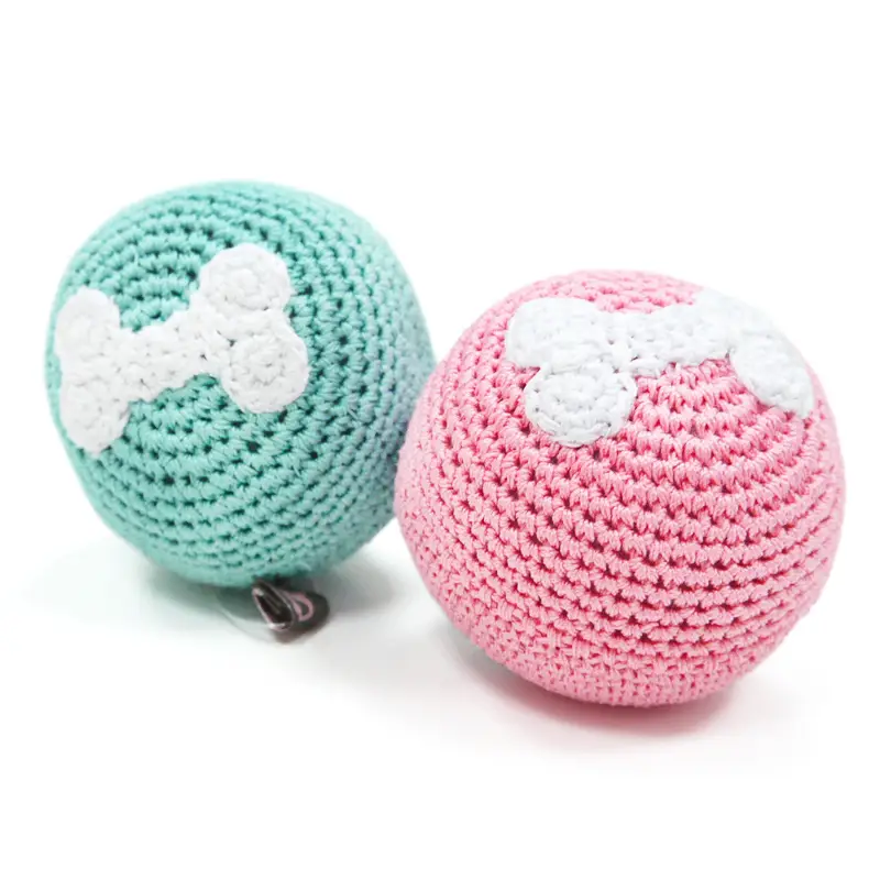 Teal and pink crochet dog toy balls with white bone details and metal tag