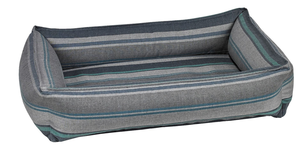 Striped fabric dog lounger bed with gray base, teal trim, and open bolstered sides