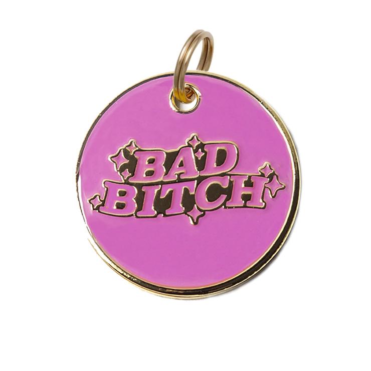 Round purple dog tag with gold border, hanging ring, "BAD BITCH" graphic with stars