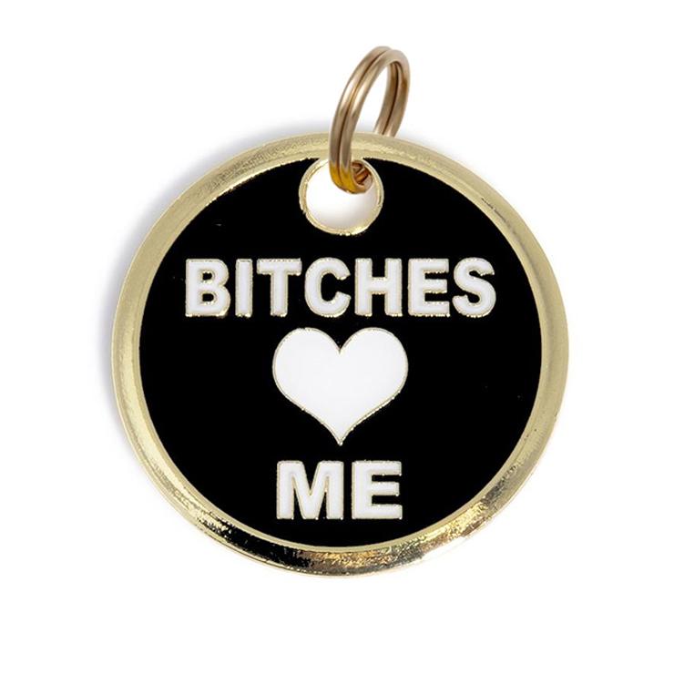 Round black dog ID tag with gold border, 'BITCHES' and 'ME' text and heart; loop