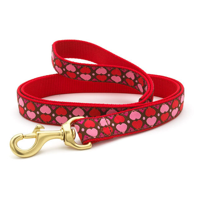 Red dog collar with pink hearts, gold D-ring and buckle, flat lay view