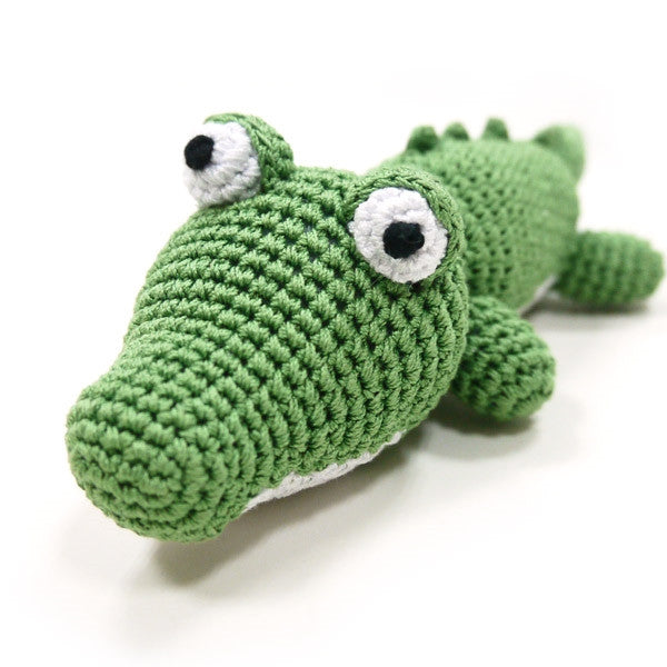 Crocheted green alligator dog toy with squeaker, close-up with white eye patches