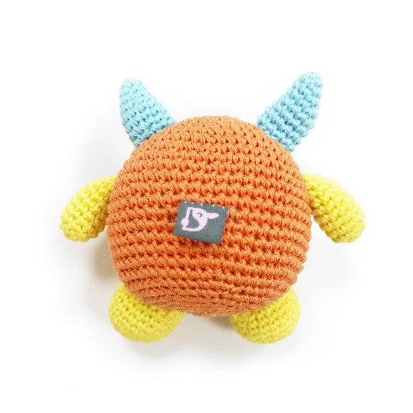 Crocheted monster dog toy with squeaker, orange round body with back tag and blue horns