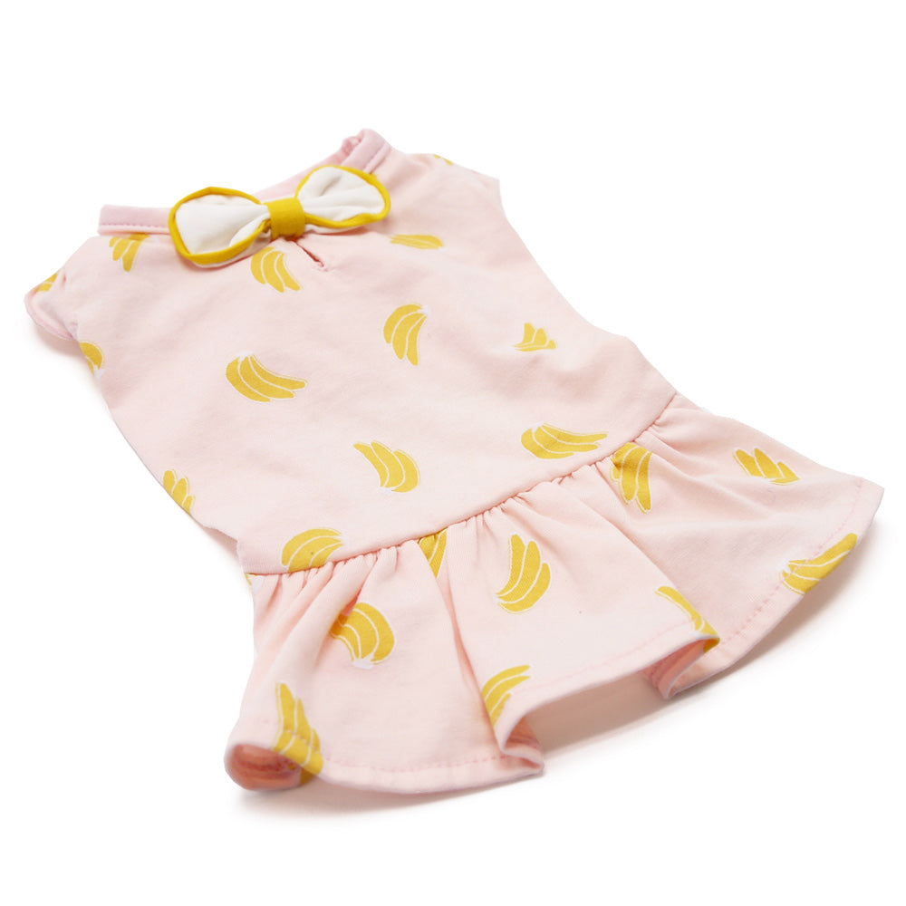 Pink banana-print dog dress laid flat, yellow bow detail on top