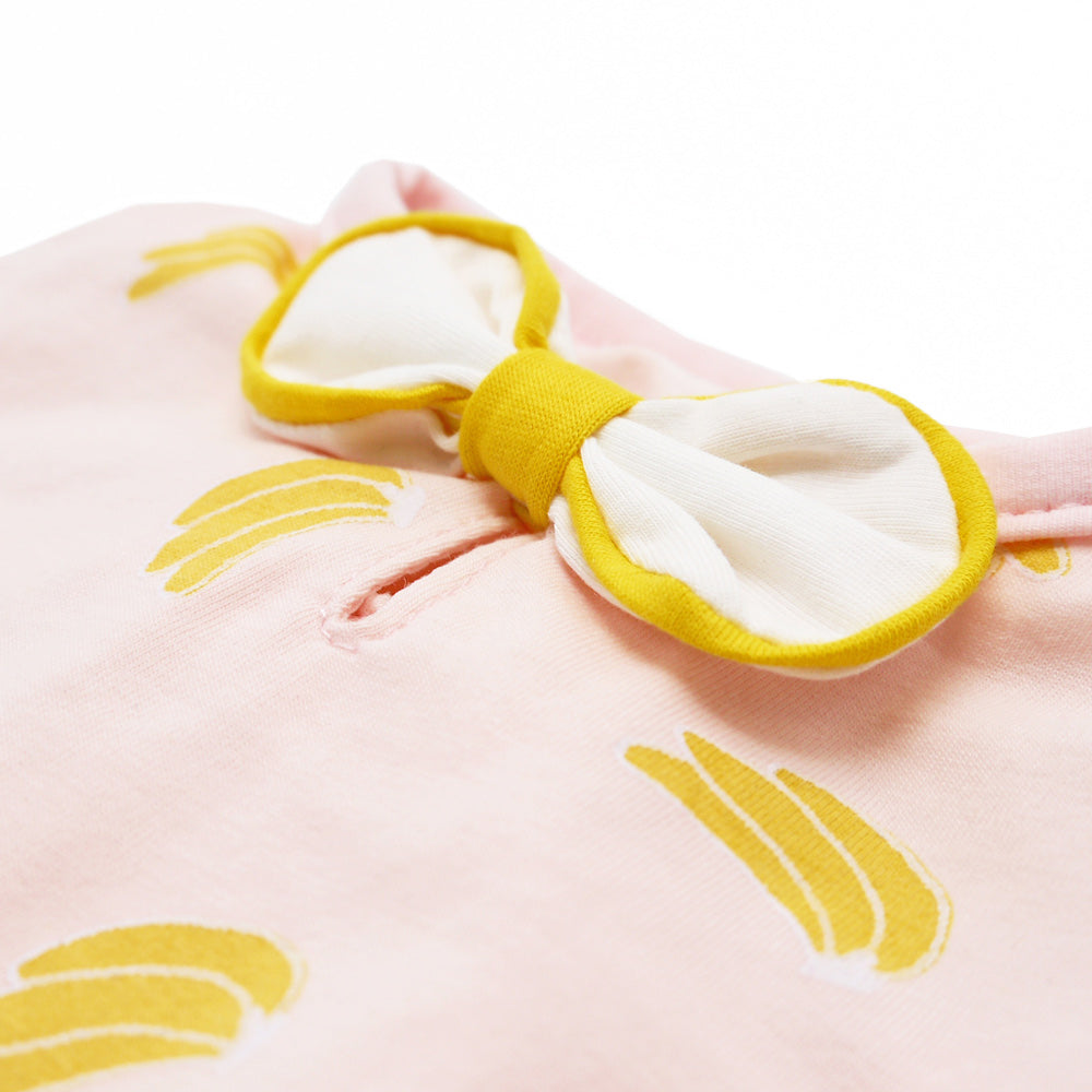 Pink banana-print dog dress fabric close-up with yellow-and-white bow