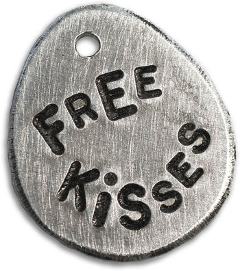 Silver hand-stamped dog tag reading 'FREE KISSES HISS'