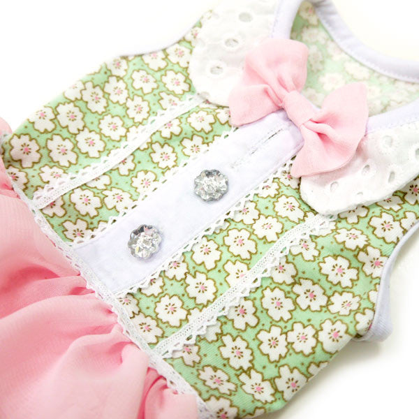 Dog dress detail: green floral fabric, white eyelet collar, pink bow and silver buttons