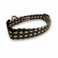Daisy-pattern dog collar with black band, white flowers, yellow centers, and pink tag