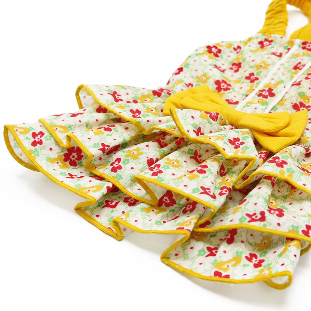 Folded floral dog dress with yellow trim, ruffled tiers, and bow at chest