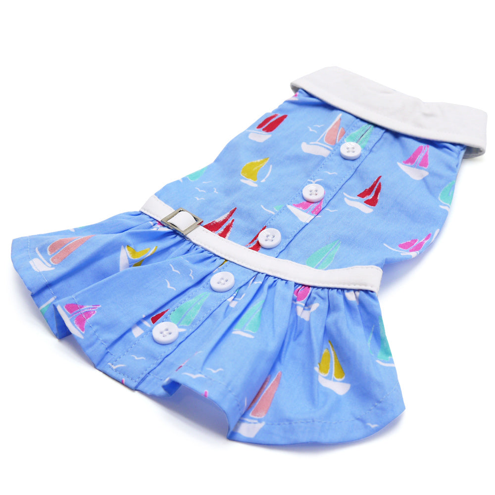 Blue sailboat print dog dress laid flat, with white collar trim and button front