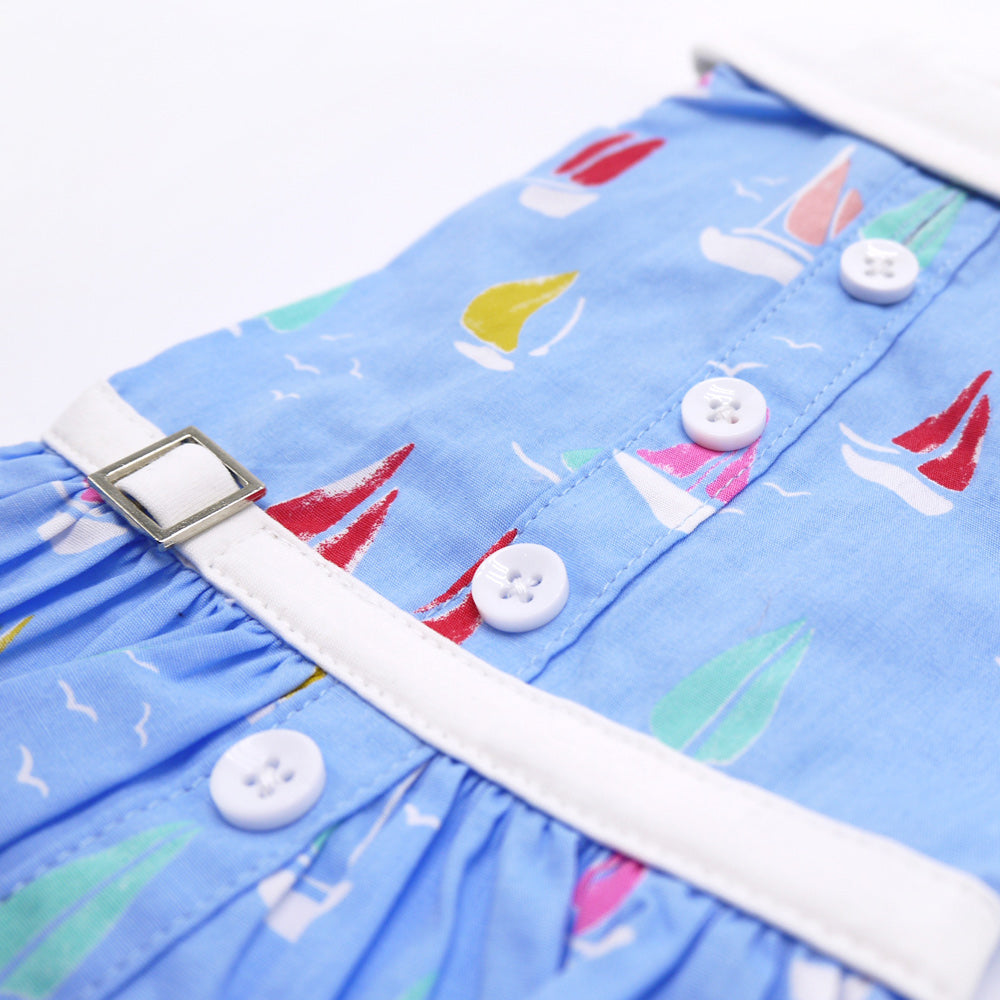 Blue sailboat dog dress detail with white trim, round buttons, and adjustable belt