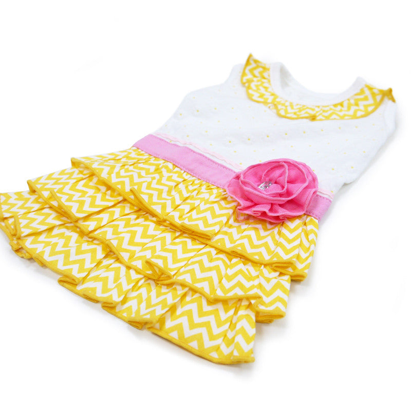 Dog dress close-up: white top with pink band, layered yellow chevron skirt, rose at waist