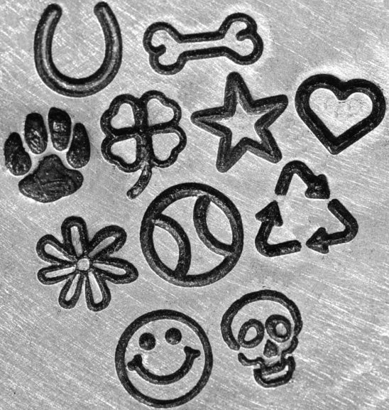 Hand-stamped silver dog tag with paw prints, hearts, stars, and bone icons