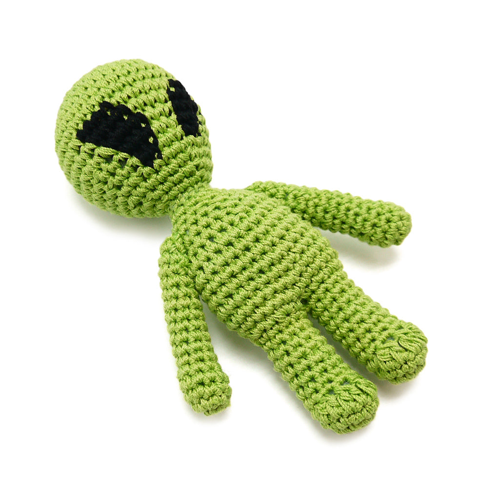 Crocheted green alien dog toy with black eye patch, lying with outstretched limbs