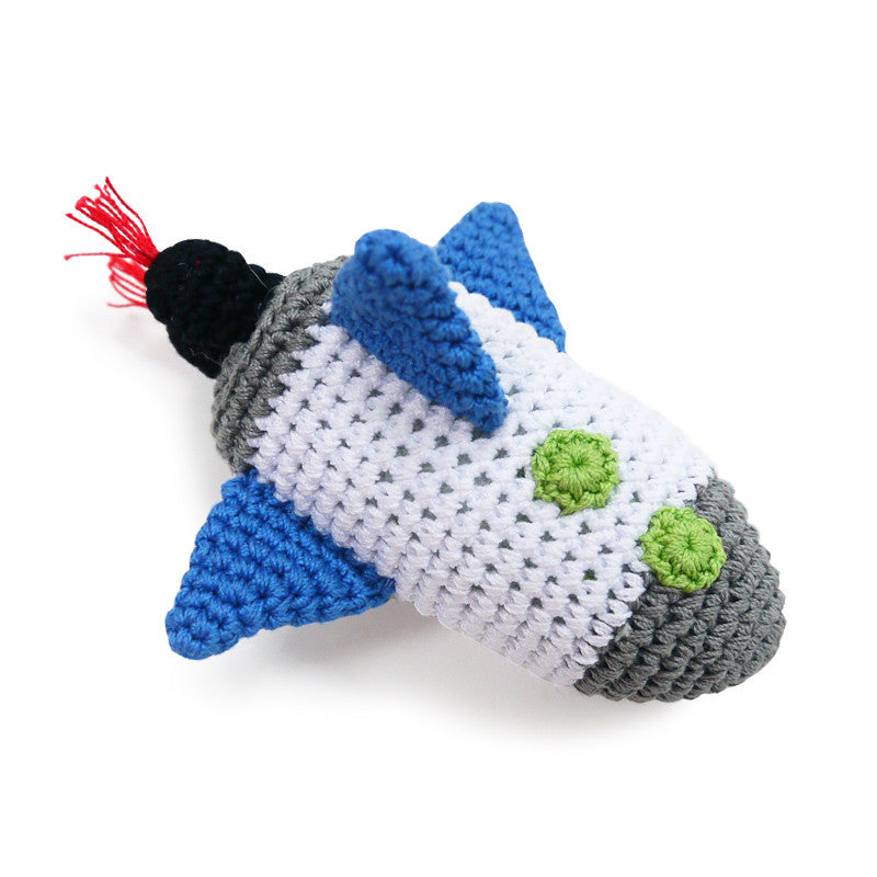 Crochet spaceship dog toy, white body with green windows, blue fins, black nose, red threads