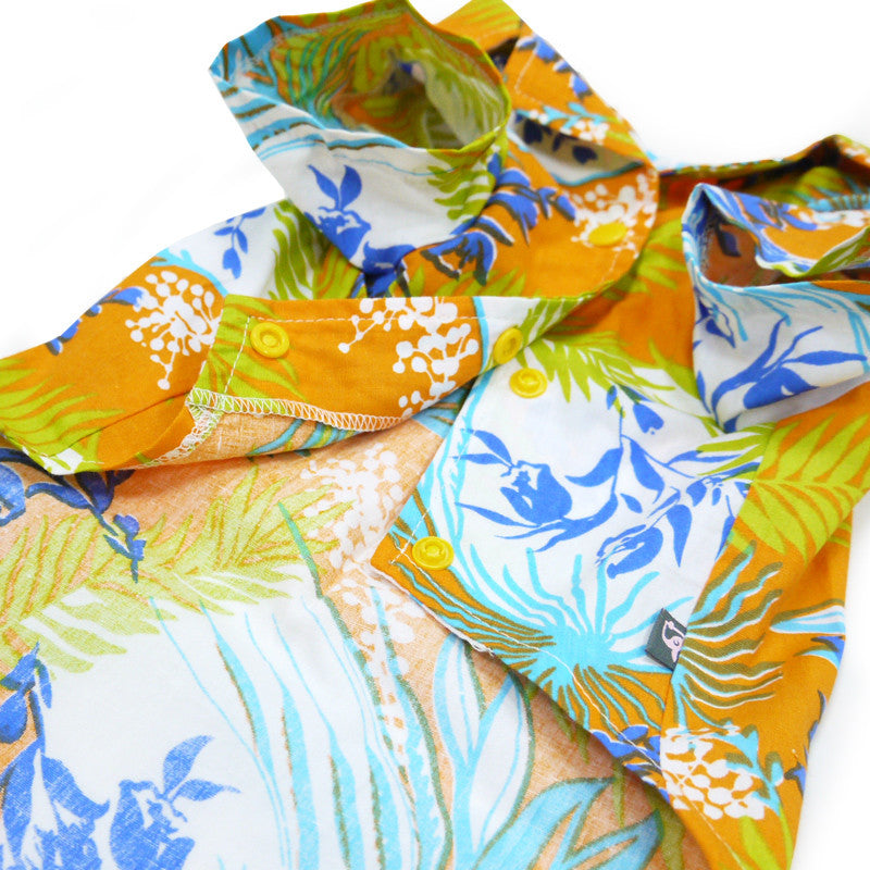 Tropical dog shirt fabric close-up in orange, blue, and green with leaf and dot prints