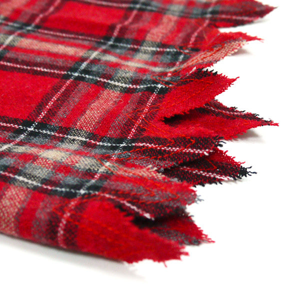 Close-up of red, black and gray plaid dog costume fabric with long fringed edge.